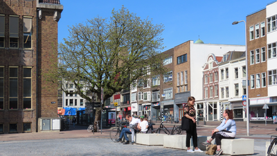 848687 Afbeelding van enkele mensen die verpozen op de betonblokken aan de noordzijde van de Neude te Utrecht, met op ...